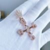 Custom cross pendant in 925 silver with VVS moissanite, plated in 14K rose gold. Center features number 2, vertical and horizontal arms with “925”, bail shaped like a small hand, displayed on palm.