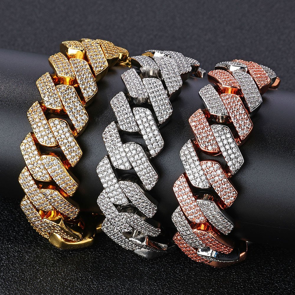 Three bold Cuban chains in gold, silver, and two-tone rose gold & silver displayed on a cylinder