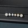 Different carat sizes of moissanite solitaire stud earrings on black background