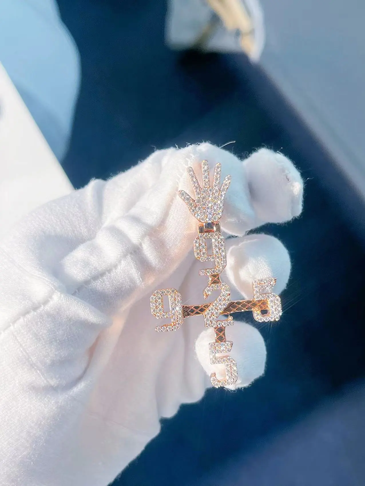 Custom diamond numbers cross pendant in 925 silver with VVS moissanite held in hand, front view