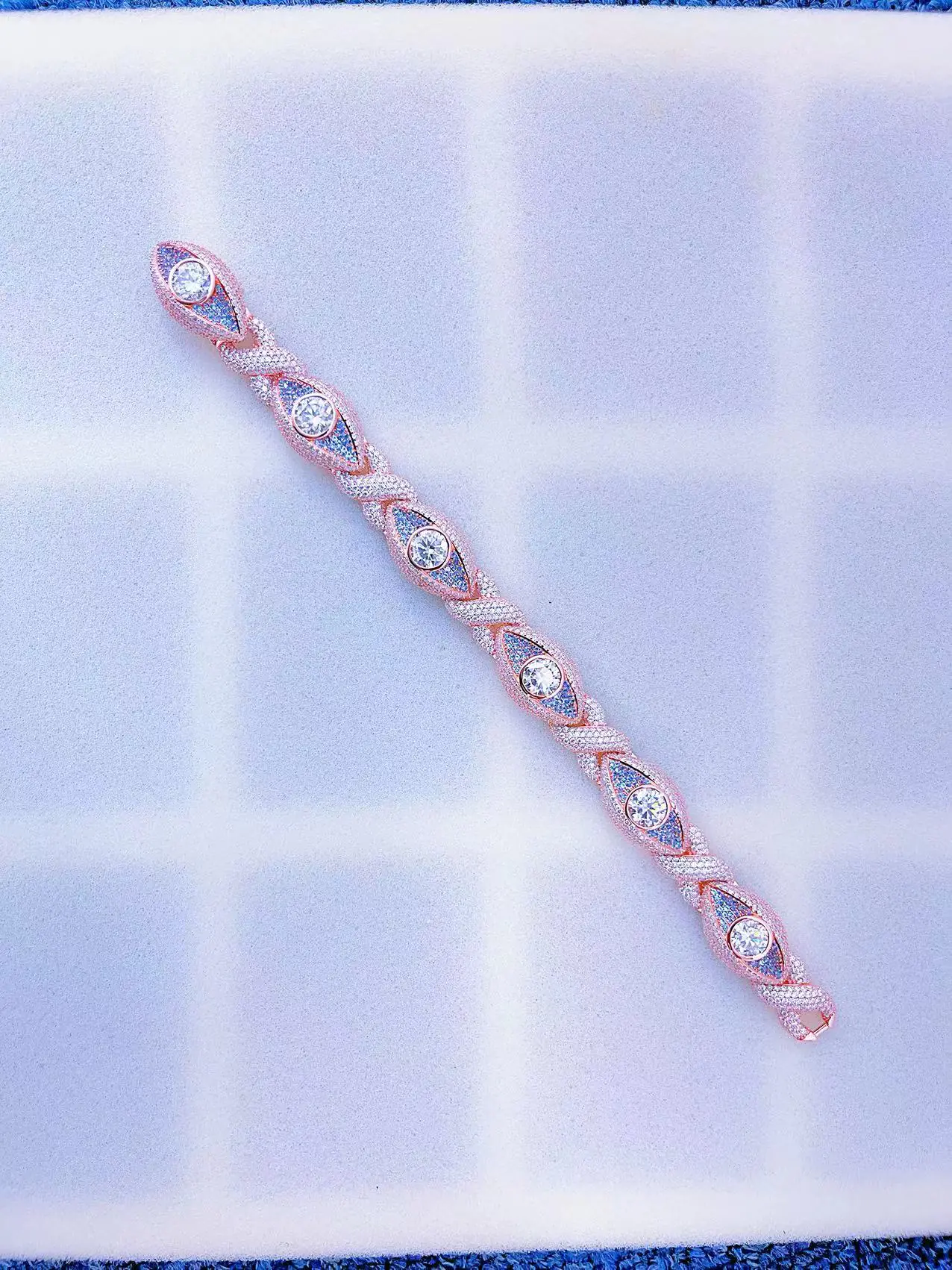 Flat laid Infinity Eyes Cuban Chain bracelet, sterling silver with VVS moissanite, rose gold plated, 8mm wide, iced out with blue and 0.5ct white stones