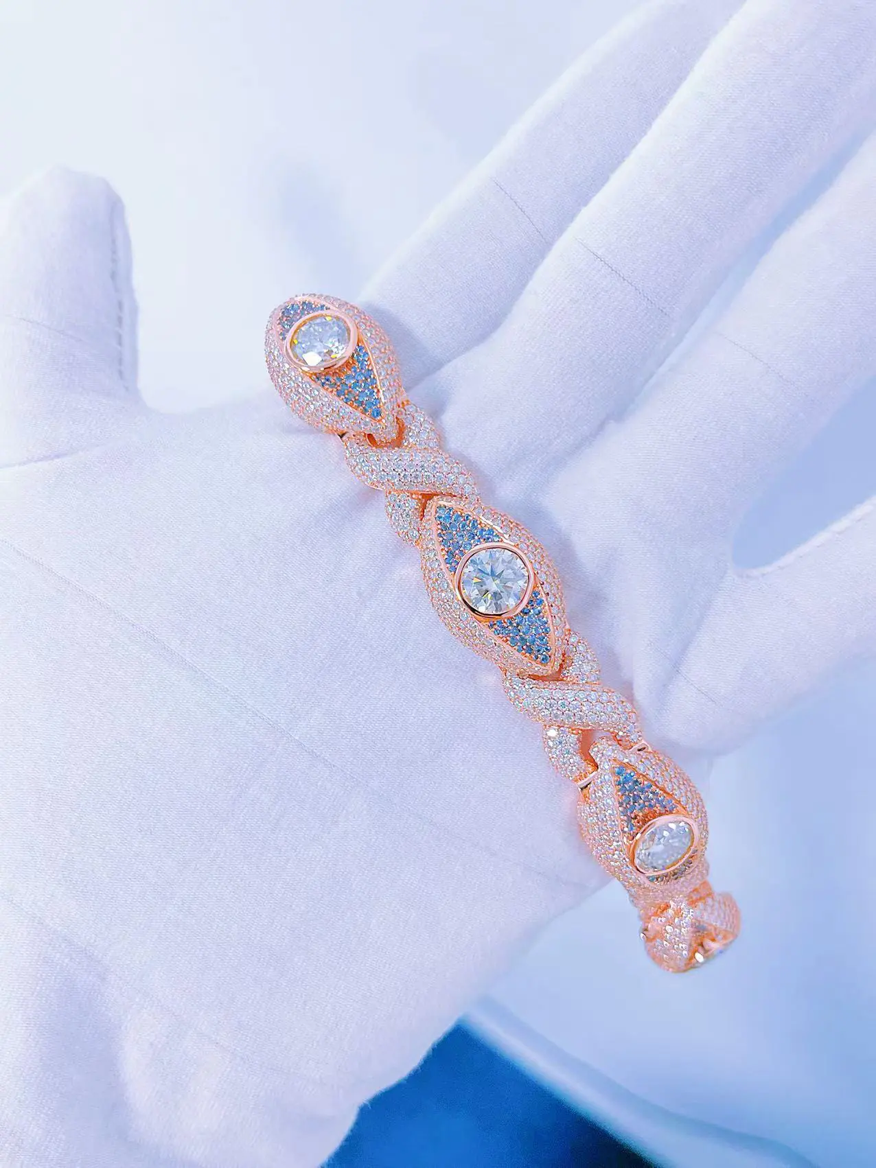 Sterling silver Infinity Eyes Cuban Chain bracelet, 8mm wide, rose gold plated, VVS moissanite, close up showing blue and 0.5ct white stones on hand