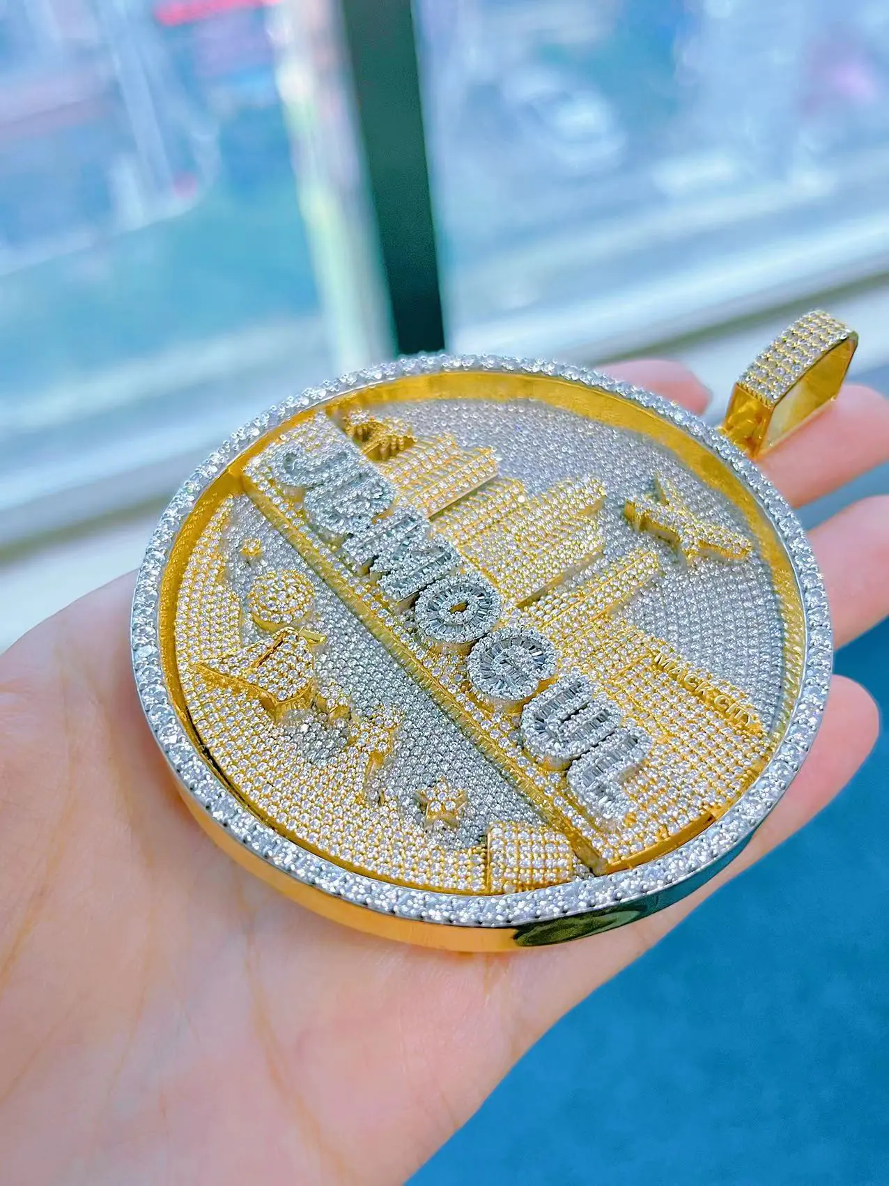 Close up to custom round skyline pendant in 925 silver with VVS moissanite, gold-plated skyline and white gold-plated background, fully iced.