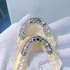 Top-down view in hand of custom fully iced grillz in 925 silver with VVS moissanite,   14K white gold plating,   fully set with round-cut stones.