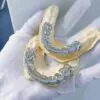 Top-down view in hand of custom fully iced grillz in 925 silver with VVS moissanite,   14K white gold plating,   fully set with round-cut stones.