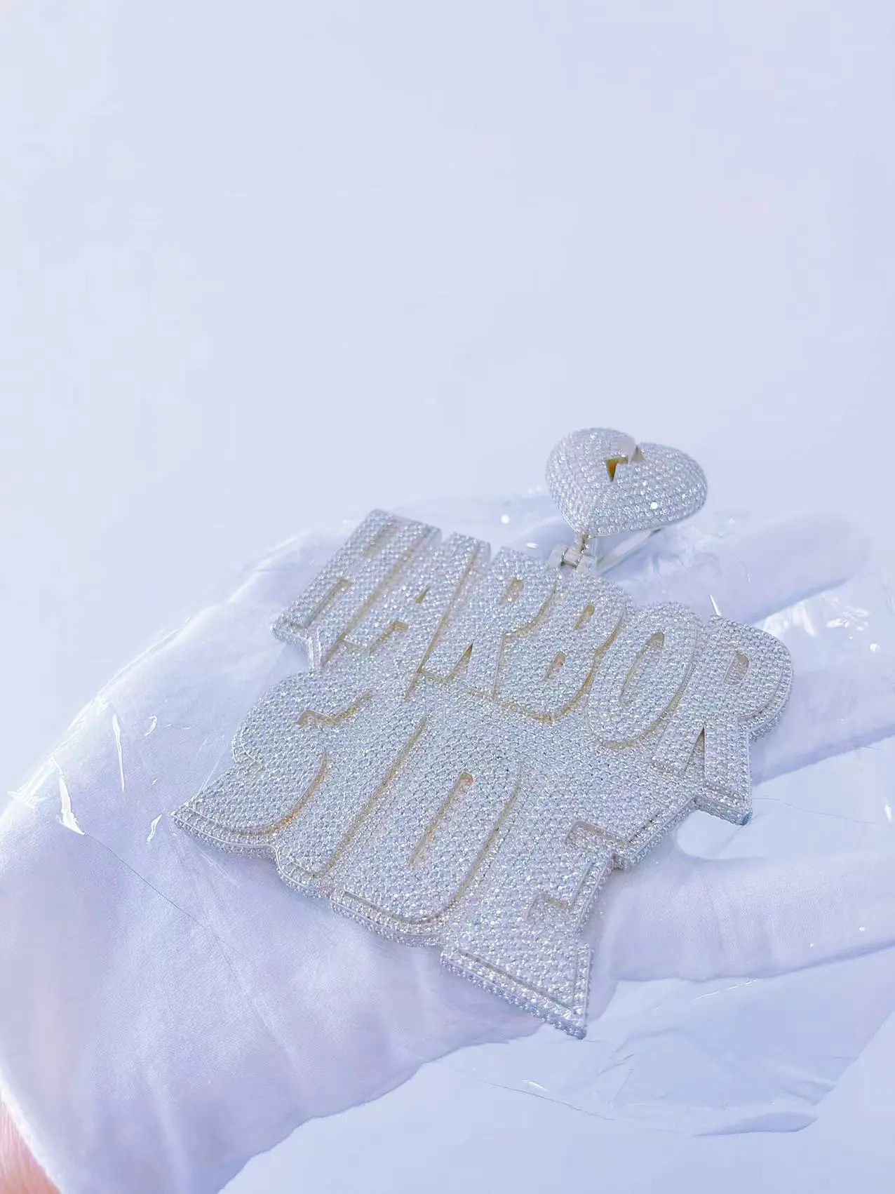 Tilted hand view of custom large letter name pendant in 925 silver with VVS moissanite, plated in 18K white gold, showing raised letters integrated with the base, no welding seams.