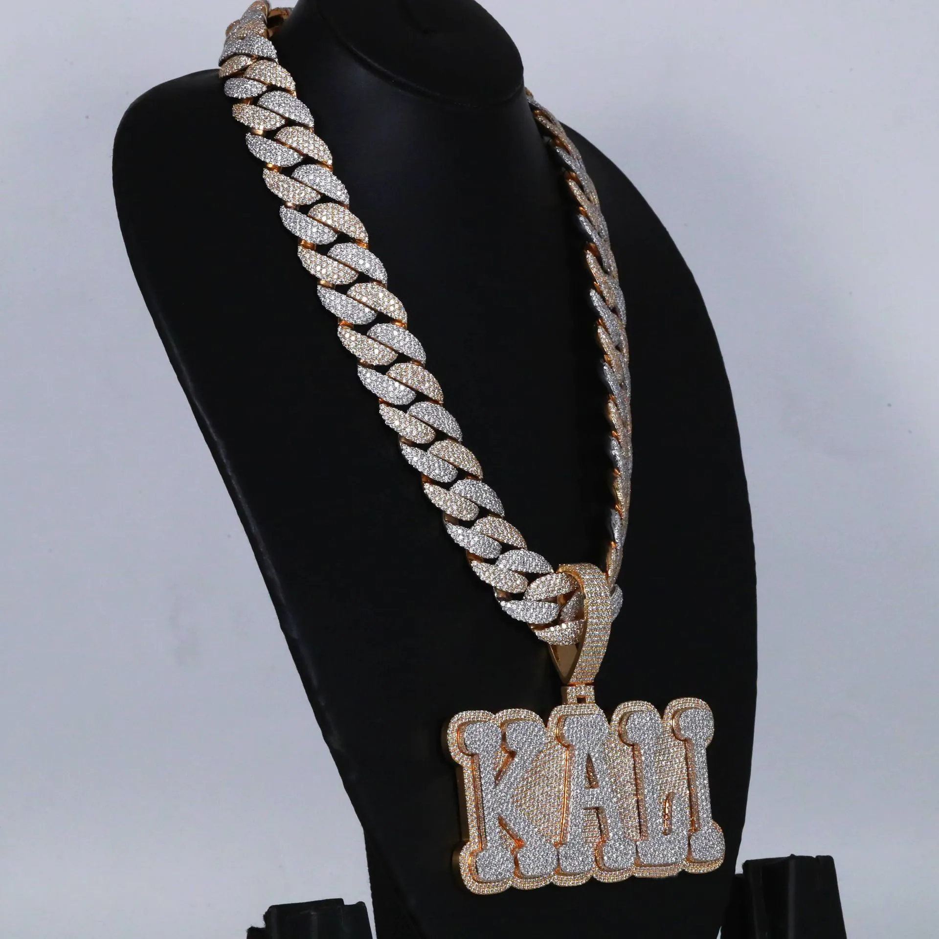 Right side view of custom large letter pendant in 925 silver with VVS moissanite, two-tone gold and white gold plating, hanging on 18mm fully iced Cuban link chain, worn on mannequin.