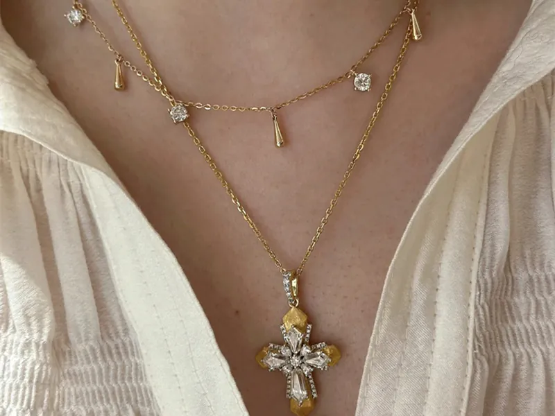 Wearing a custom 18K gold layered necklace from Kegan Design Jewelry with a personalized cross pendant.