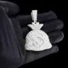 Close up of Moneybag Pendant in brass with CZ stones,   14K white gold plated,   iced out pendant held in hand,   front view