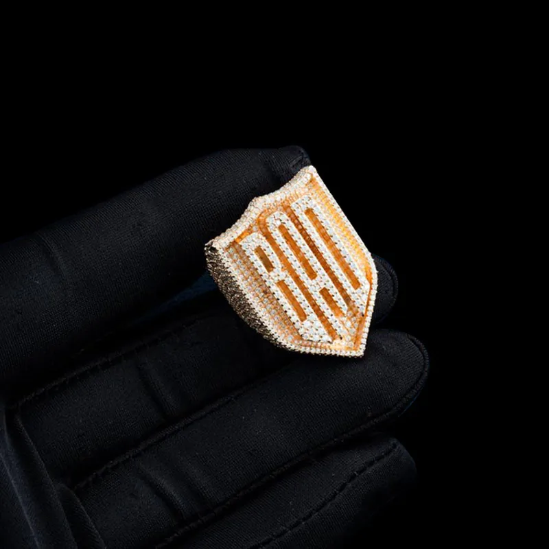 Close up of BAD Shield Ring in sterling silver with moissanite, 14K gold plated, iced out ring held in hand, front view of shield and raised letters