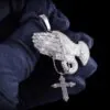 Close up of VVS Praying Hands Pendant in brass with CZ stones,   14K white gold plated,   held in hand to show intricate iced out details