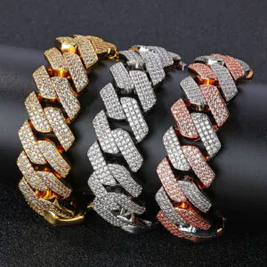 Three bold Cuban chains in gold, silver, and two-tone rose gold & silver displayed on a cylinder