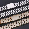 Two Cuban chains laid flat on a black background—gold chain with stones facing up,   silver chain with back side facing up to show details.