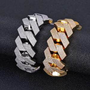 One silver and one gold 26mm oversized Cuban chain bracelet displayed on a round cylinder, simulating wrist wear.