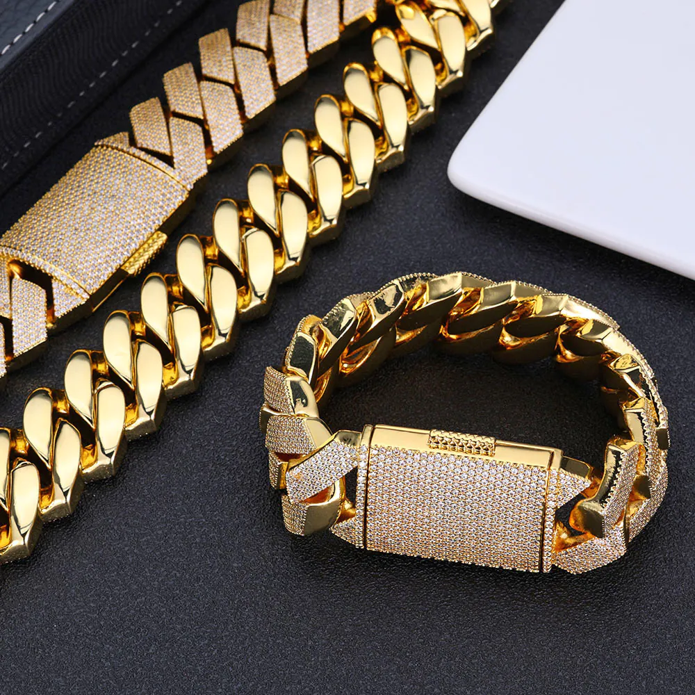 Two Gold Cuban link necklaces and one bracelet on a tabletop, necklace laid flat, bracelet clasp closed and standing upright.